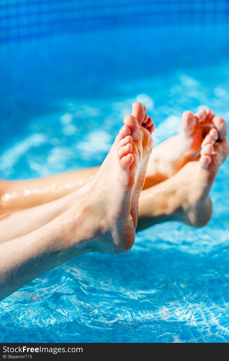 Two pairs of Female feet splashing in the pool, water splashing