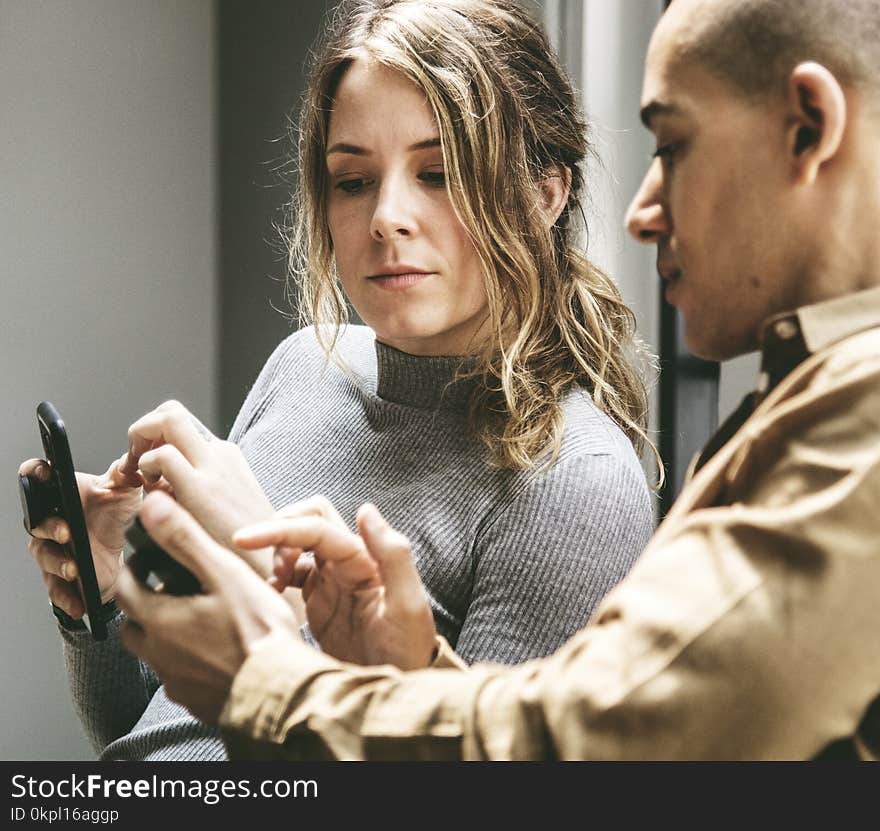 Two People in a Discussion with Mobile Phones