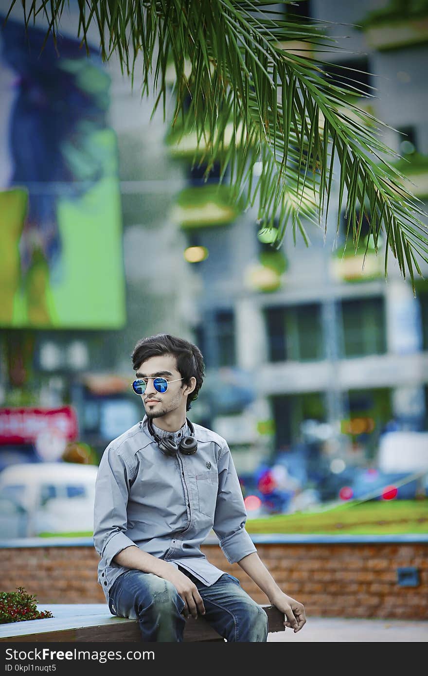 Man Wearing Gray Dress Shirt Sitting on Bench Near Building