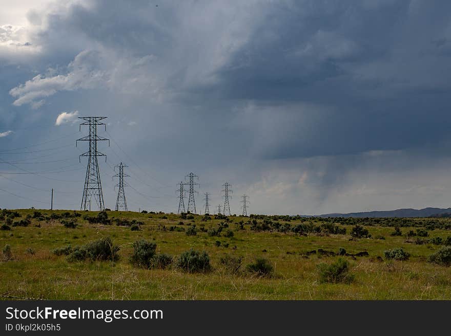 Gray Electric Post on Green Field Under White Clouds and Blue Sky