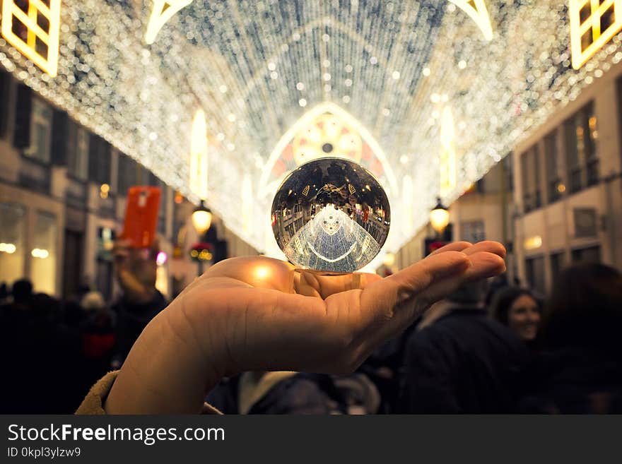 Person Holding Round Silver-colored Accessory