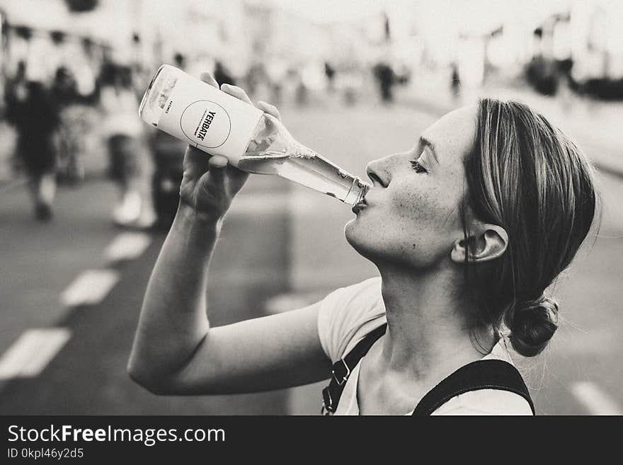 Woman Holding Glass Bottle in Grayscale Photo