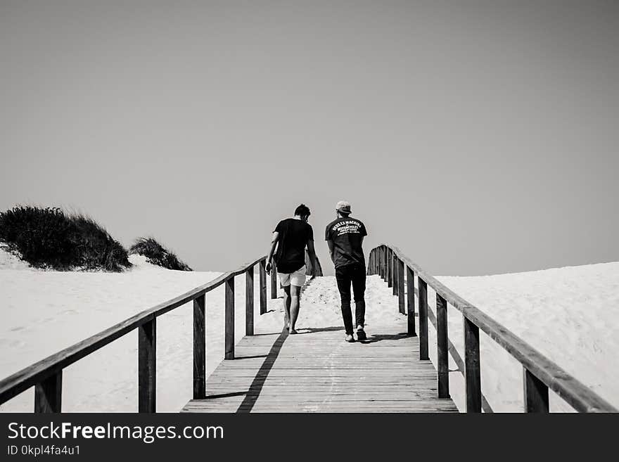 Grayscale Photography of Man and Woman Crossing Bridge