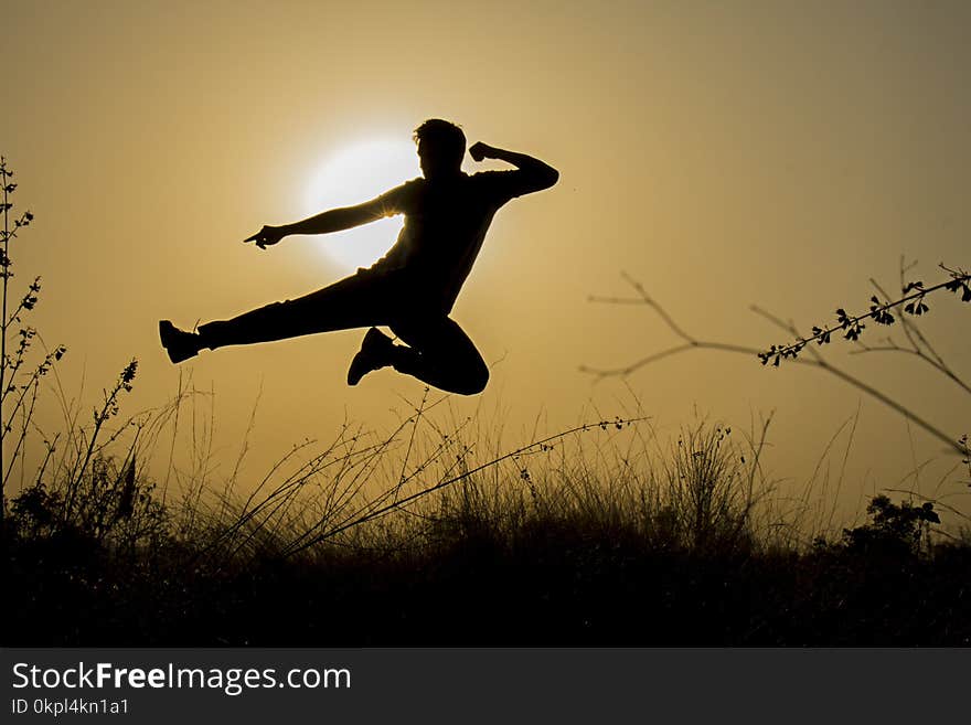 Silhouette of Man Doing Kick Jump during Sunset