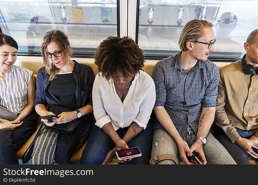 Woman Sitting Holding Smartphone Between Two Men and Two Women