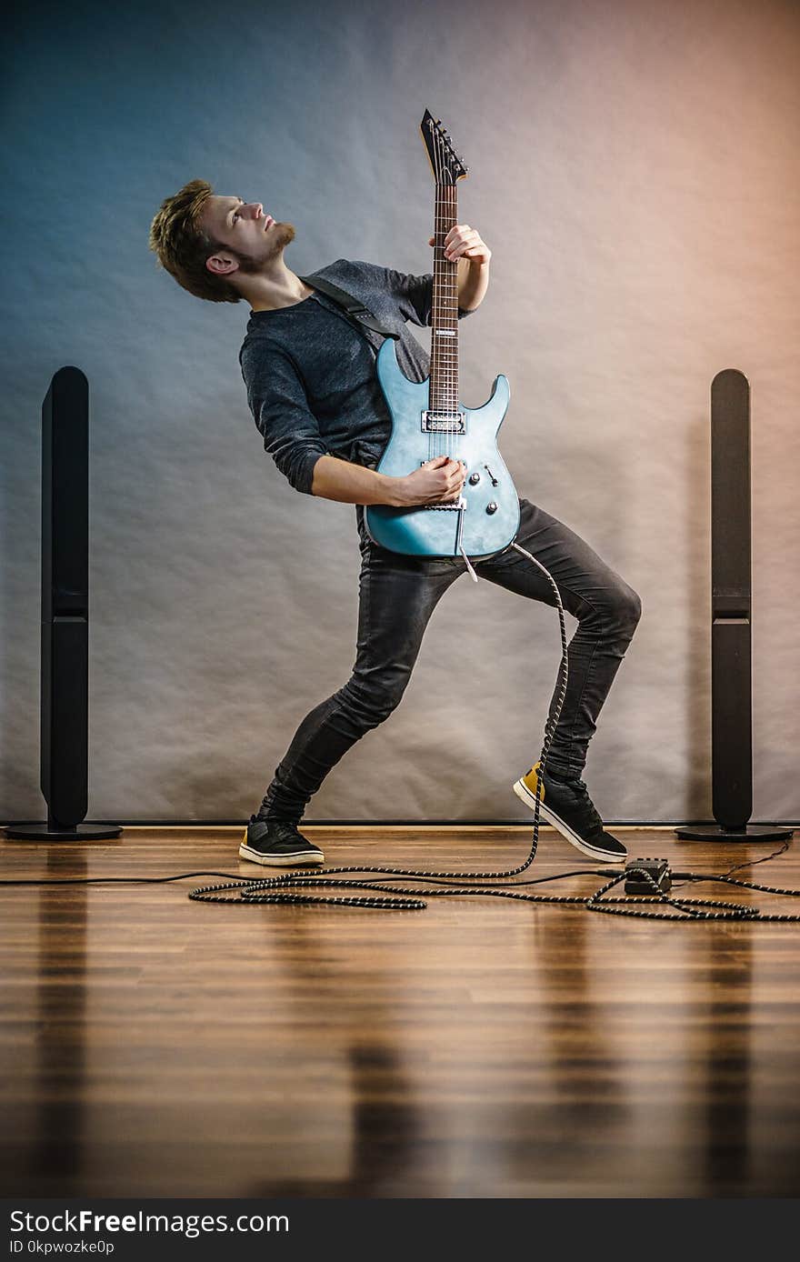 Young bearded man with electric guitar. Adult person in full length is holding instrument and playing. Hobby, music concept, on grey. Young bearded man with electric guitar. Adult person in full length is holding instrument and playing. Hobby, music concept, on grey