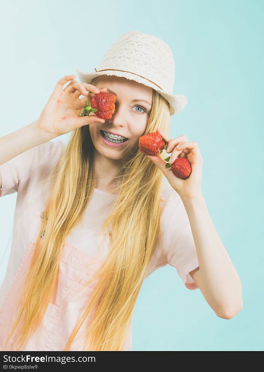 Young positive woman playing with fresh strawberries fruits, on blue. Healthy meal. Young positive woman playing with fresh strawberries fruits, on blue. Healthy meal.