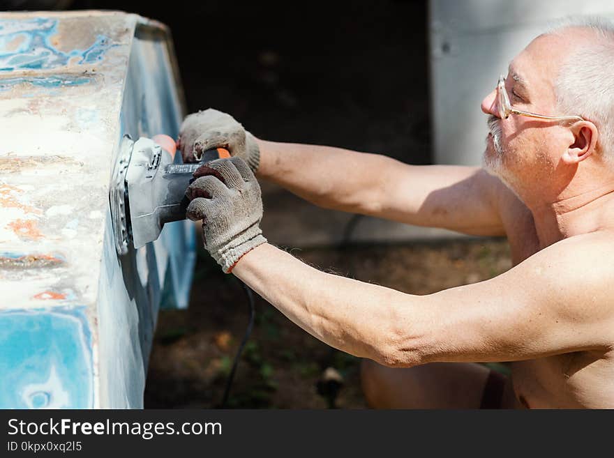 Man Is Repairing And Grinding An Old Boat