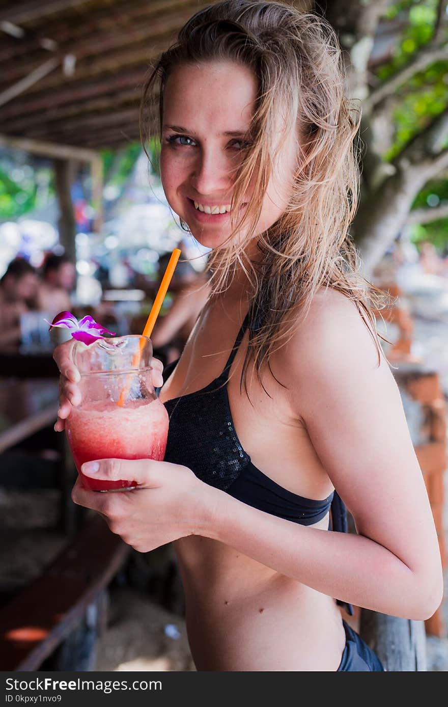 Sport fitness woman drinking healthy pink detox juice, vegetable smoothie on the beach summer outdoors. Fitness healthy