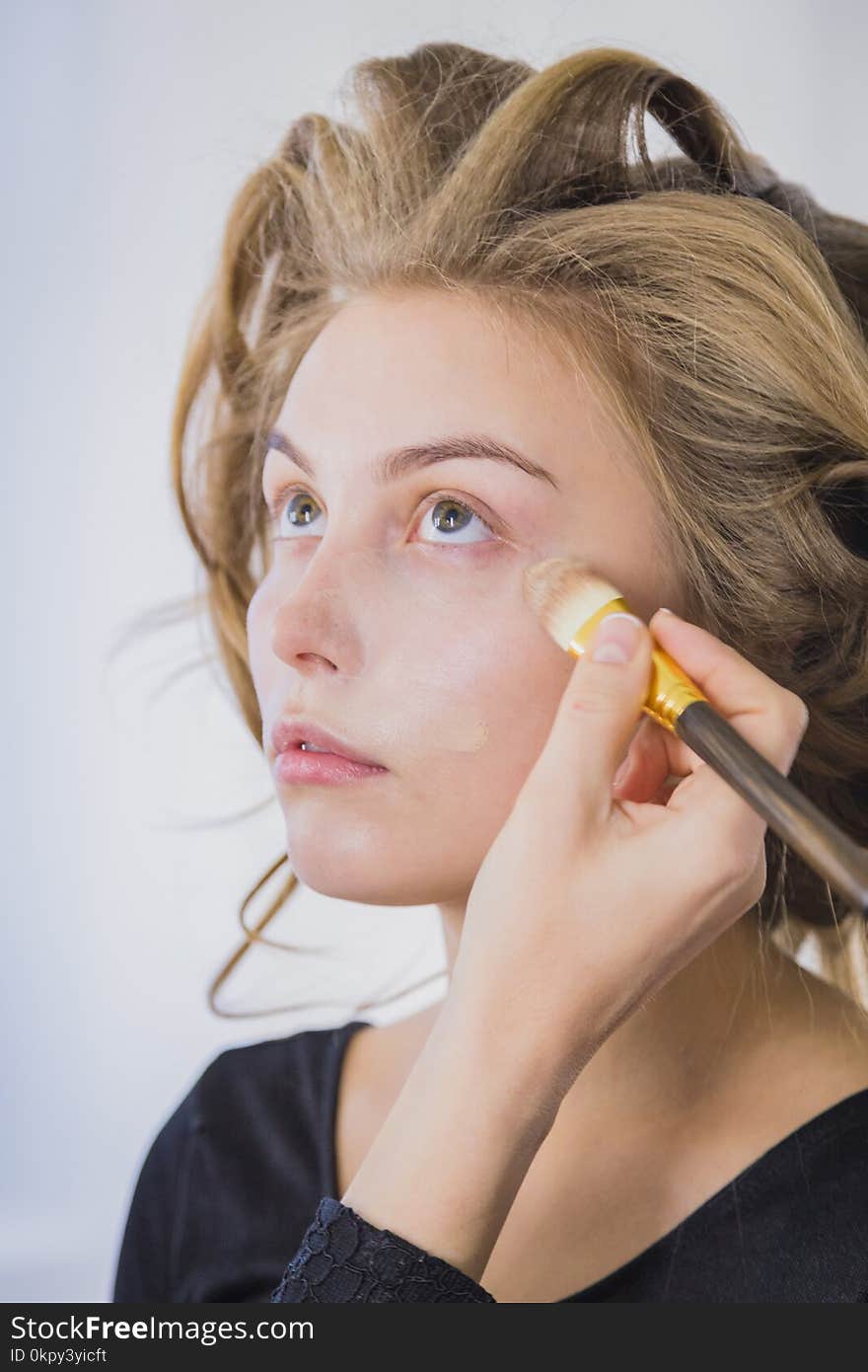 Makeup artist applying liquid tonal foundation on the face of the women in white make up room. Beauty and fashion concept. Makeup artist applying liquid tonal foundation on the face of the women in white make up room. Beauty and fashion concept