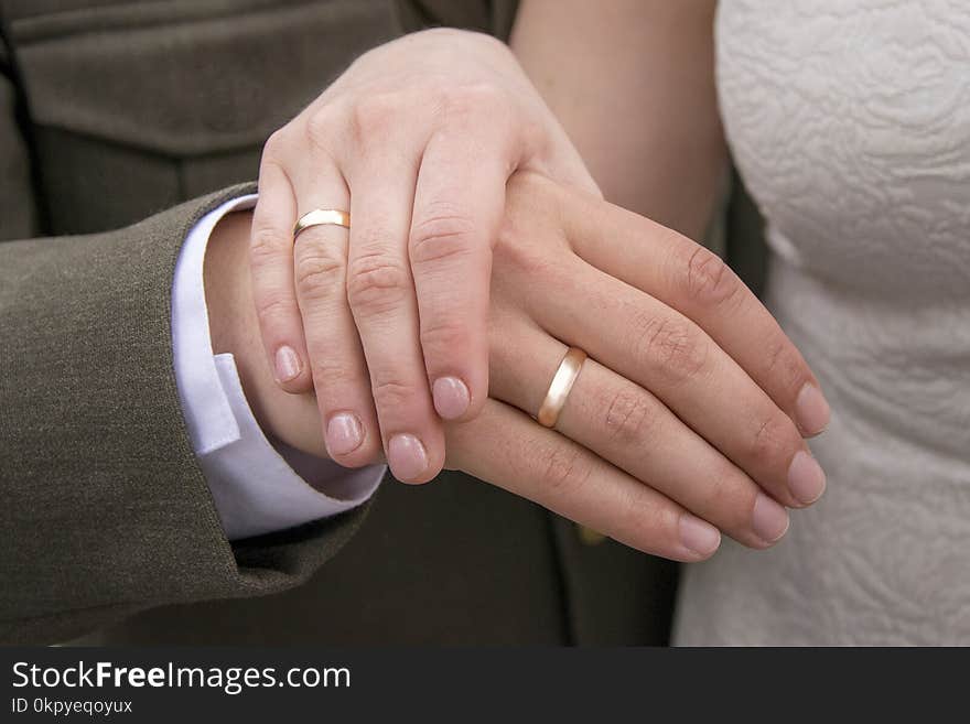 Focus on female and male hands with wedding rings. Arms of married couple. Man in official suit and woman in bright dress with pretty ornament. Focus on female and male hands with wedding rings. Arms of married couple. Man in official suit and woman in bright dress with pretty ornament