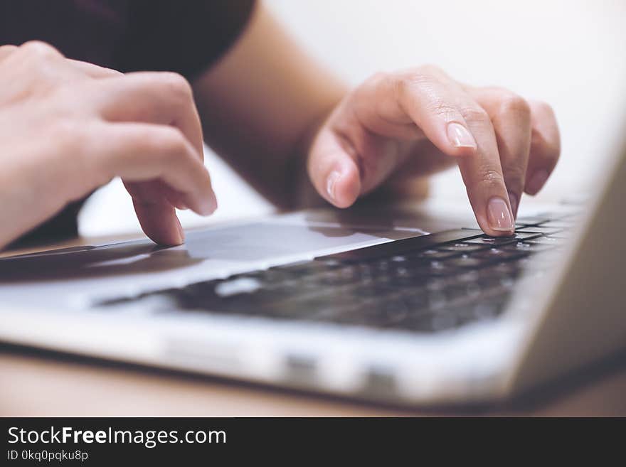 Closeup image of hands working and typing on laptop keyboard with blur background