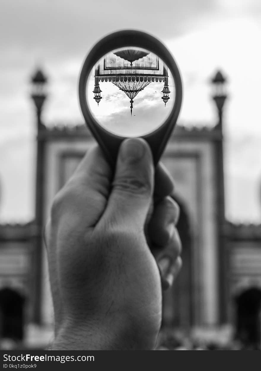 Grayscale Photo of Person Holding Round Magnifying Glass