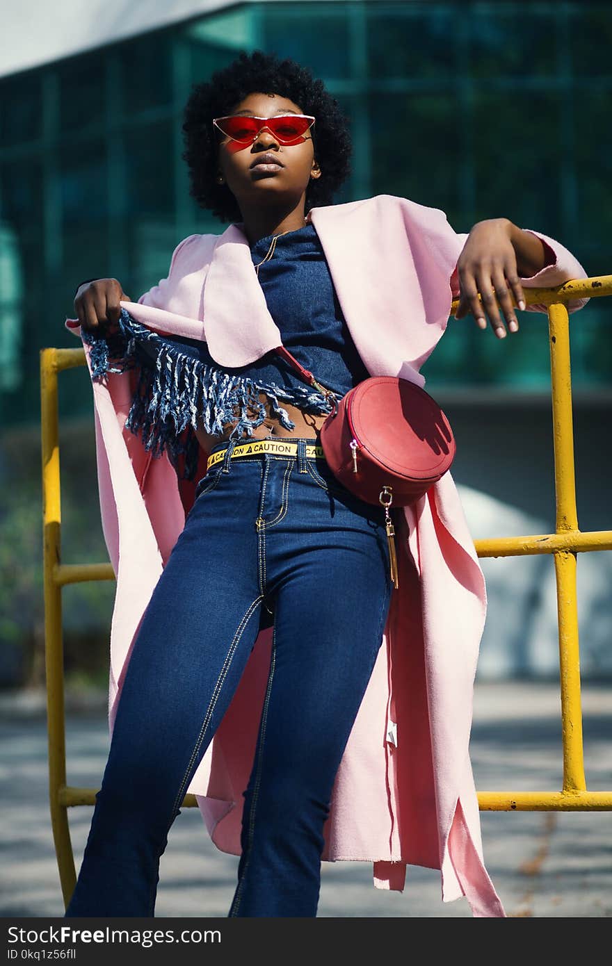 Woman Wearing Jeans Leaning on Yellow Metal Bar