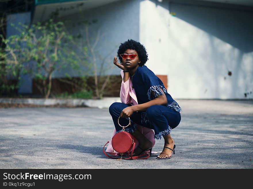 Woman Wearing Blue Shirt and Pants Holding Red Leather Barrel Bag