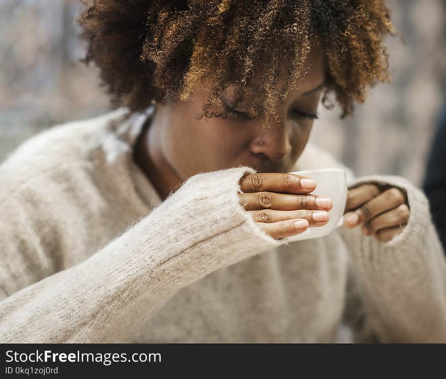 Woman Holding a Cup While Drinking