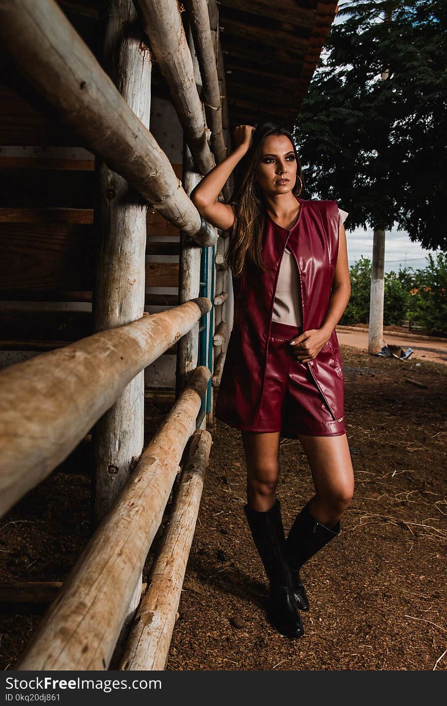 Woman Wearing Maroon Leather Sleeveless Jacket Beside Horse Stable