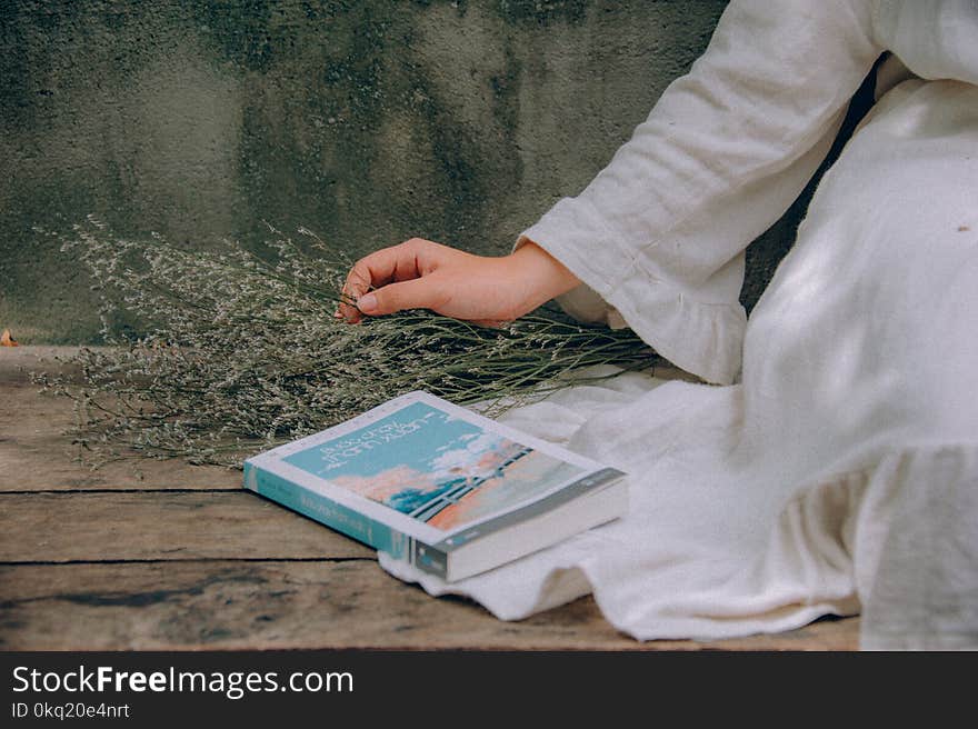 Blue and White Book Beside Woman Wearing White Dress