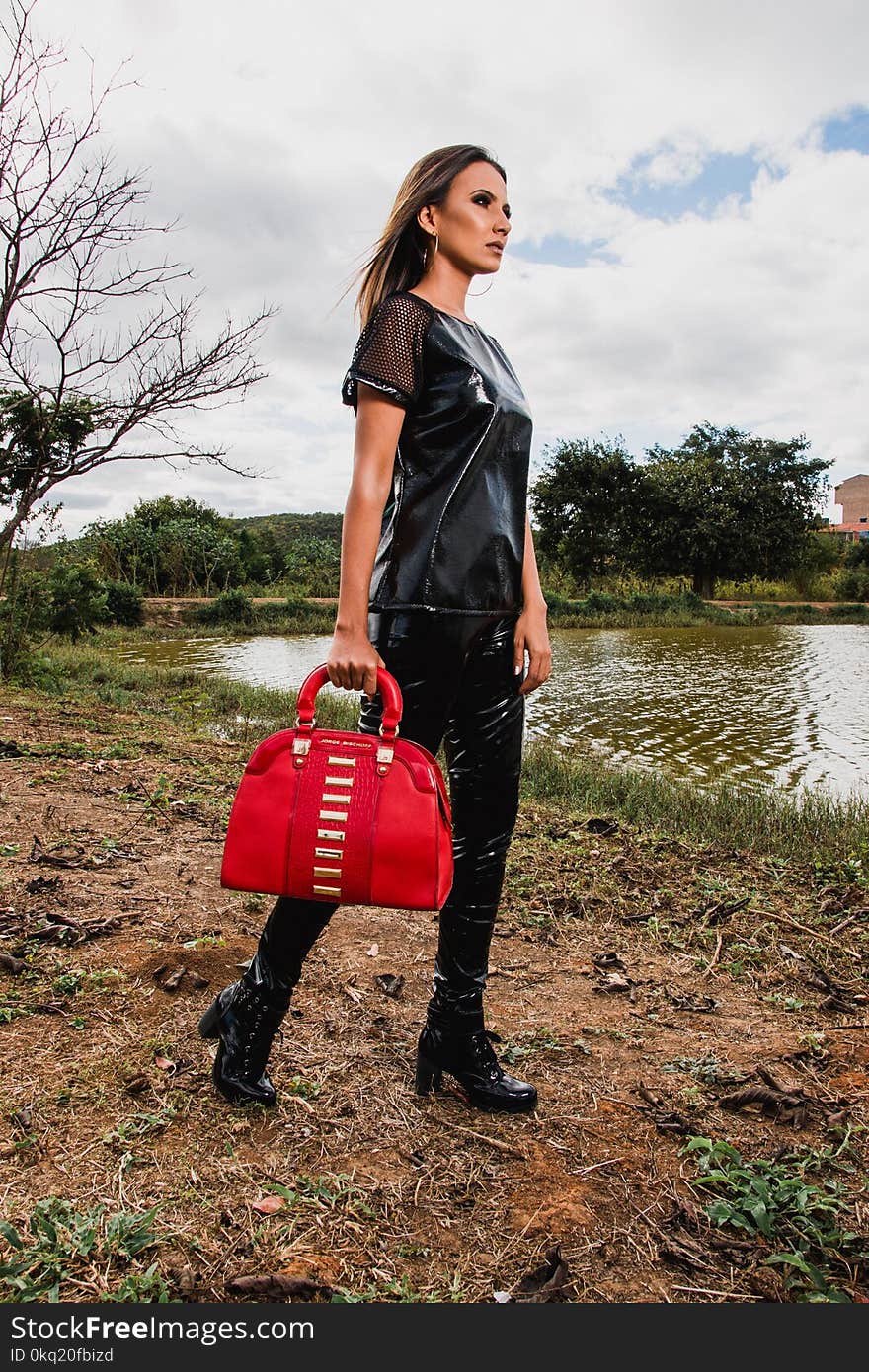 Woman Wearing Black Suit Holding Red Leather Duffel Bag during Day