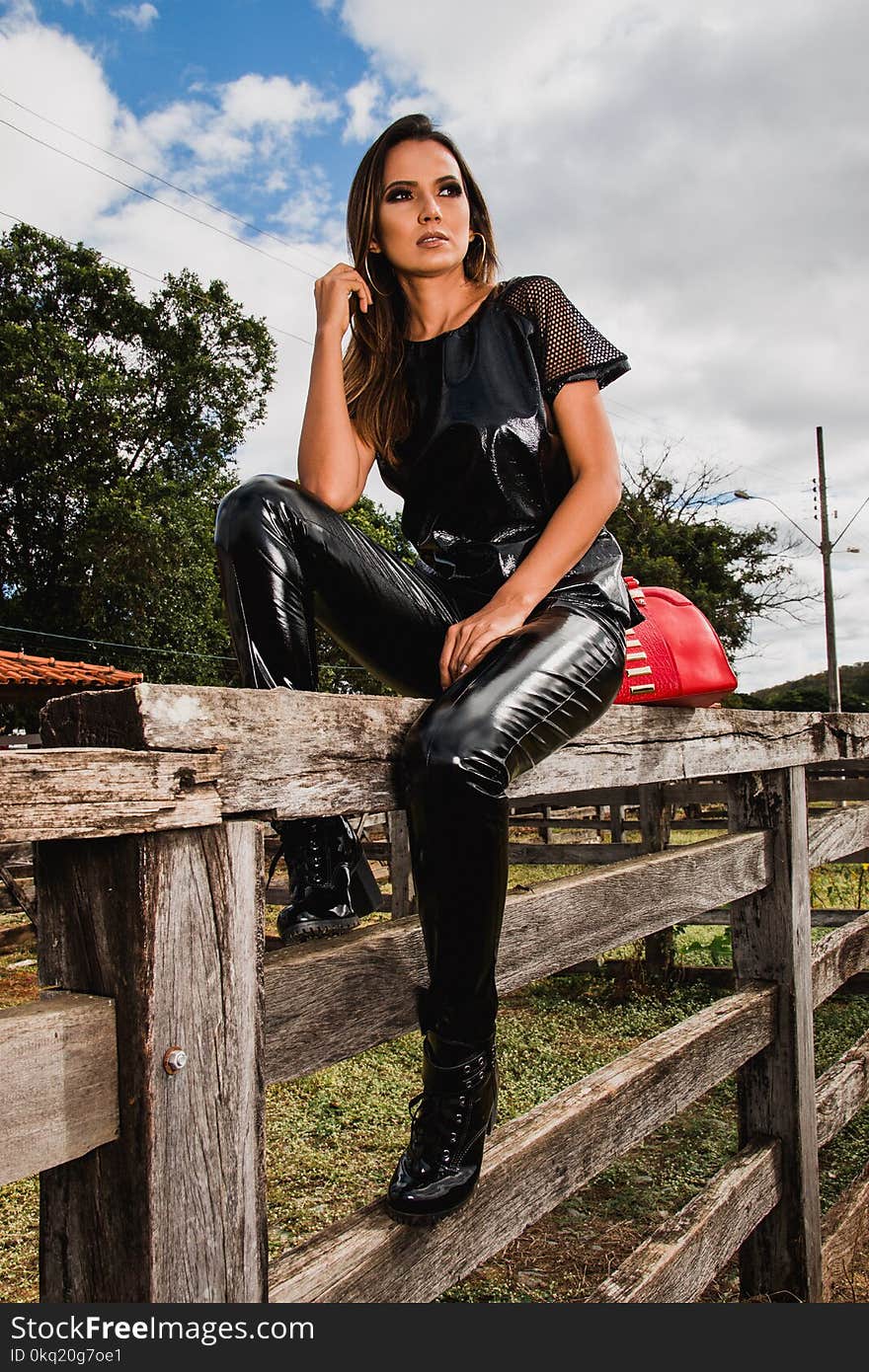 Woman Wearing Black Suit on Farm Sitting on Fence