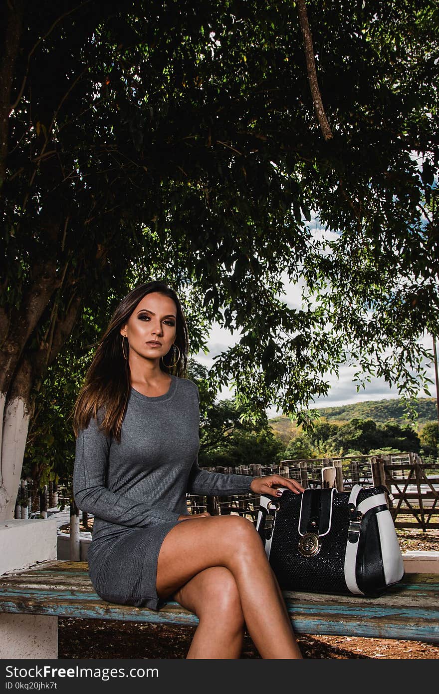 Woman Wearing Gray Long-sleeved Dress Sitting on Bench