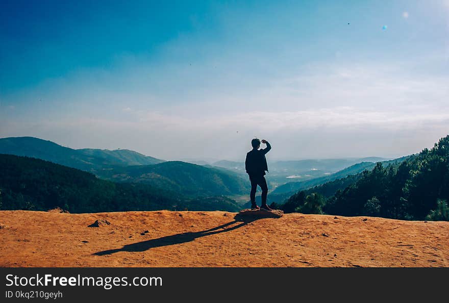 Silhouette of Man Standing on Mountain Cliff