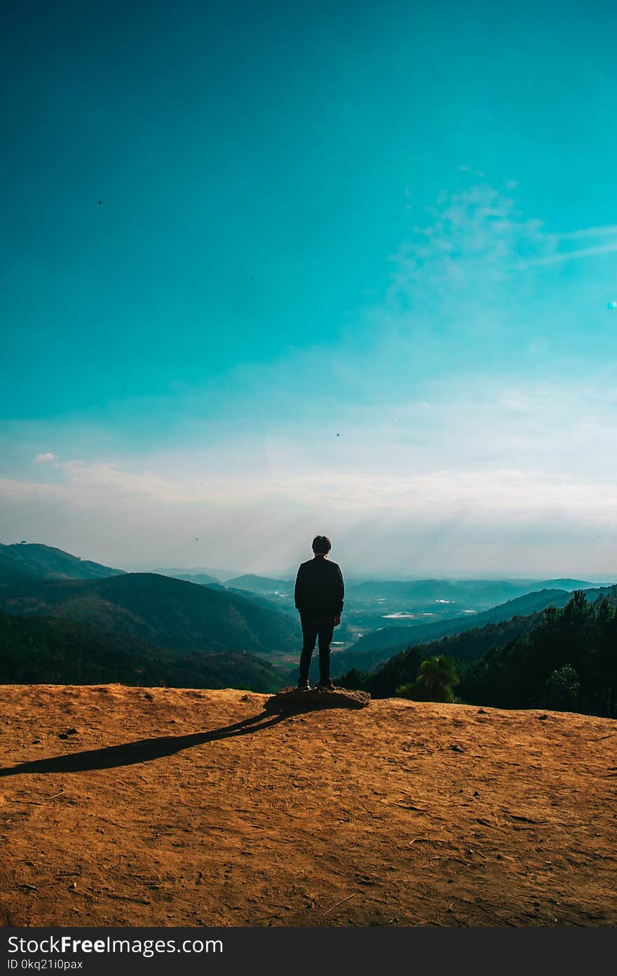 Silhouette of Person Standing on Hill Under Clear Blue Sky