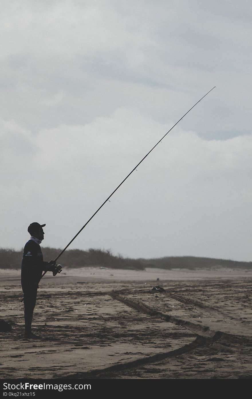 Man Standing Holding a Fishing Rod