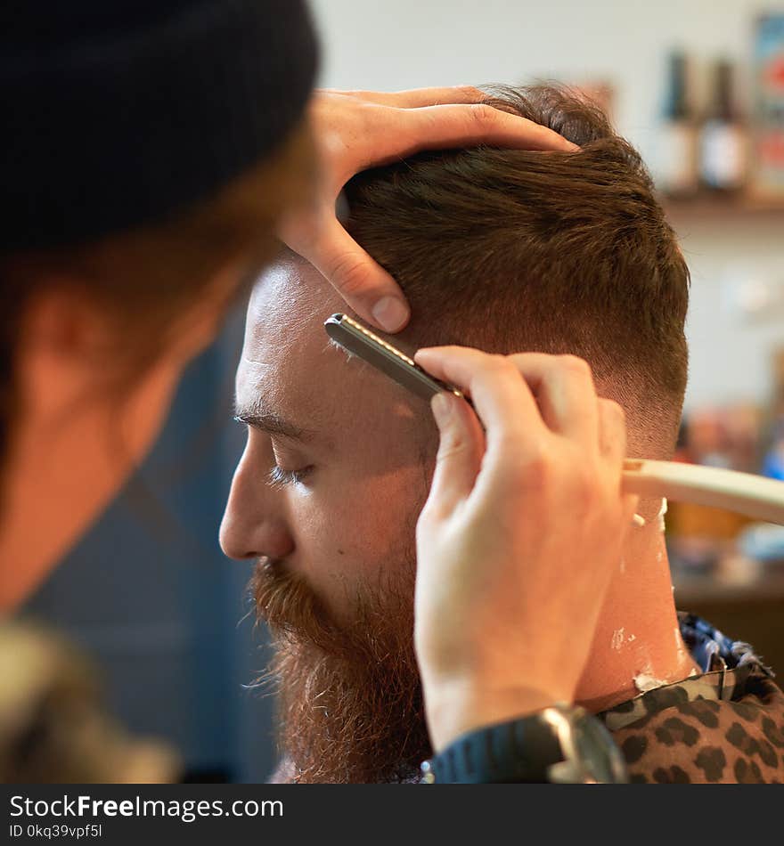 Close up of a hairdresses work for an attractive young blond man at the barber shop.