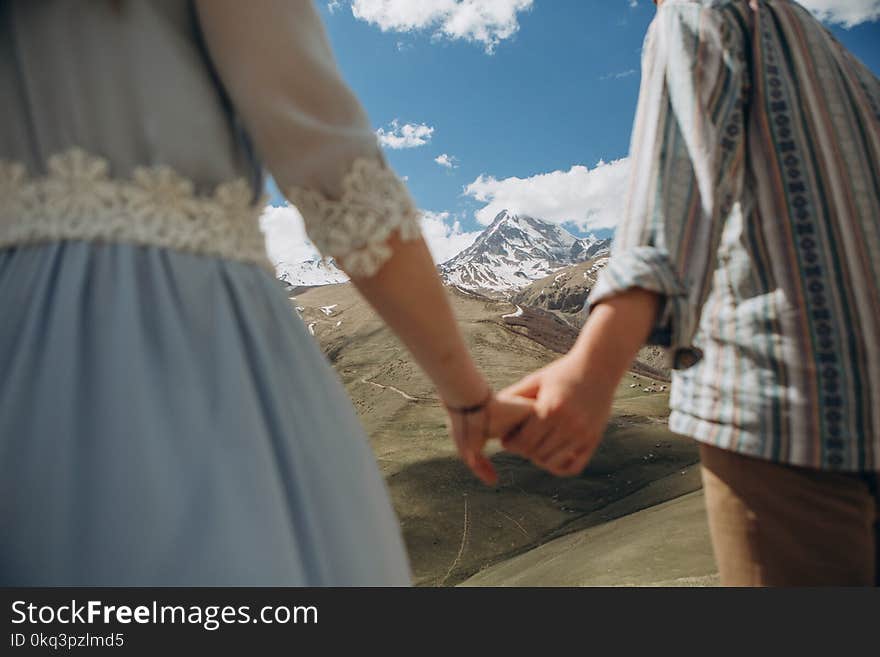 Big mountain with a snowy peak between the hands of a loving couple in sunny. Big mountain with a snowy peak between the hands of a loving couple in sunny