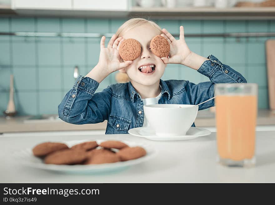 Moment of happiness. Beautiful kid showing her tongue while making faces, being in the kitchen. Moment of happiness. Beautiful kid showing her tongue while making faces, being in the kitchen