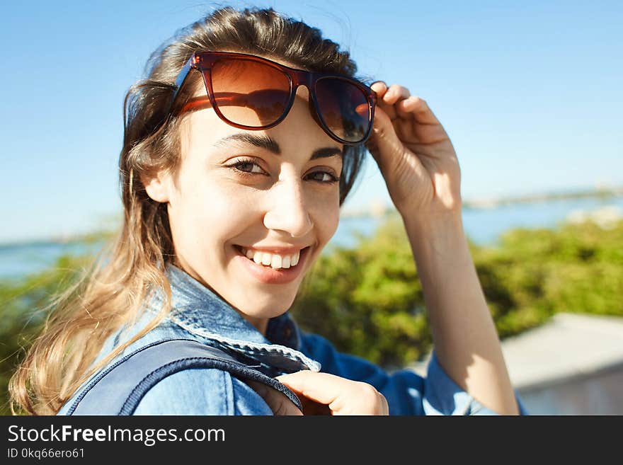 Portrait of a young smiling attractive woman with sunglasses at sunny day . woman walking and poses in cityscape. Portrait of a young smiling attractive woman with sunglasses at sunny day . woman walking and poses in cityscape.