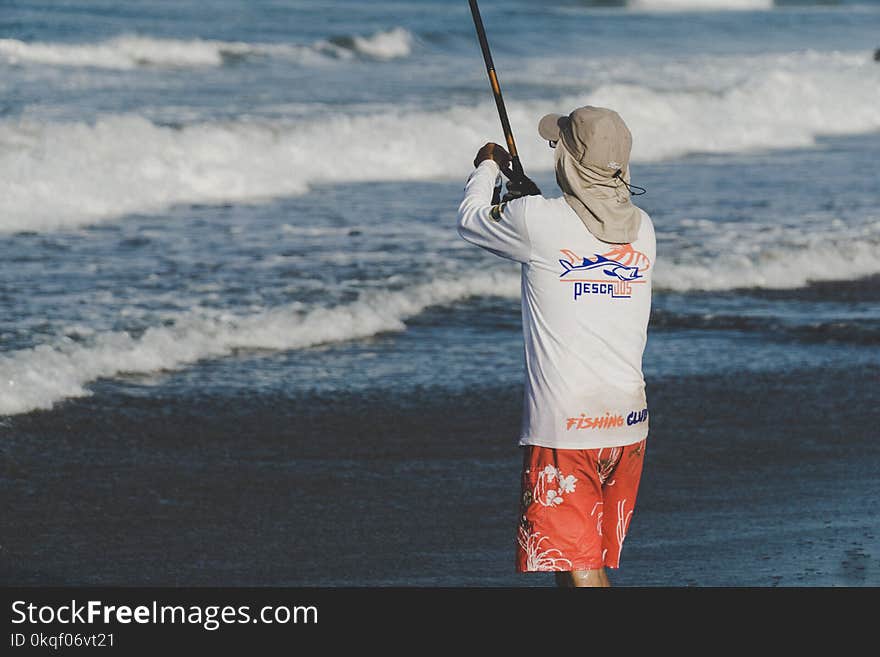 Person Holding Fishing Rod on Beach