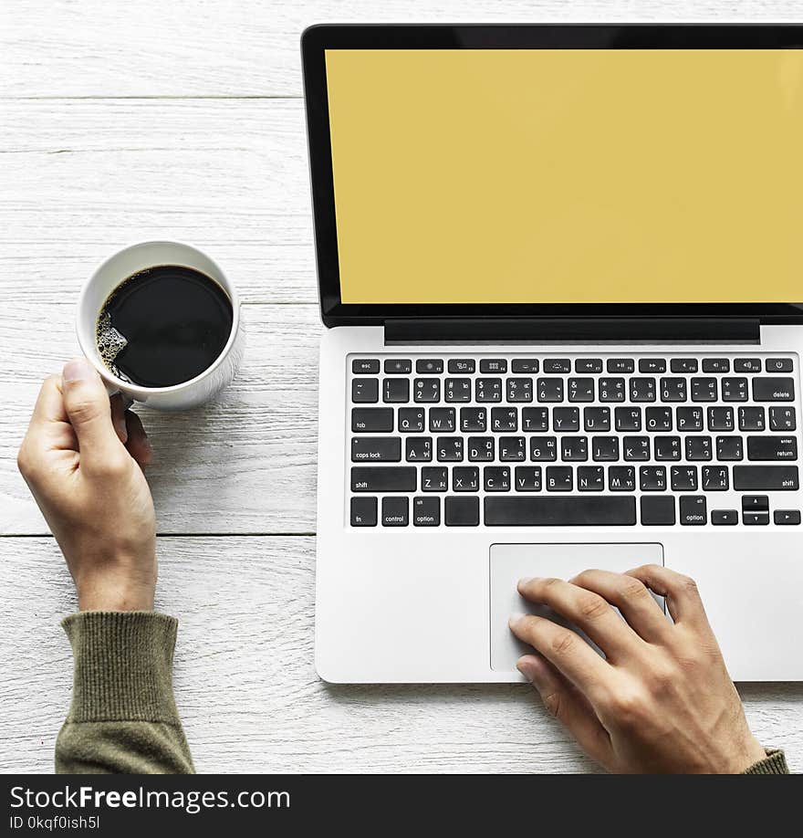 Person&#x27;s Hand on Laptop and Holding Coffee