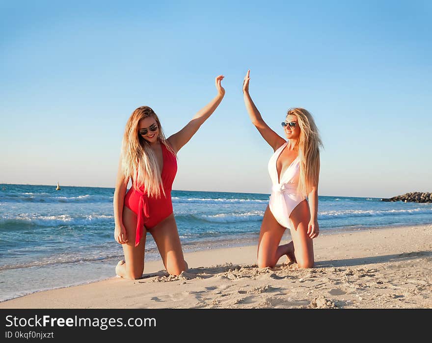 Two Woman Kneeling on White Sand Beach