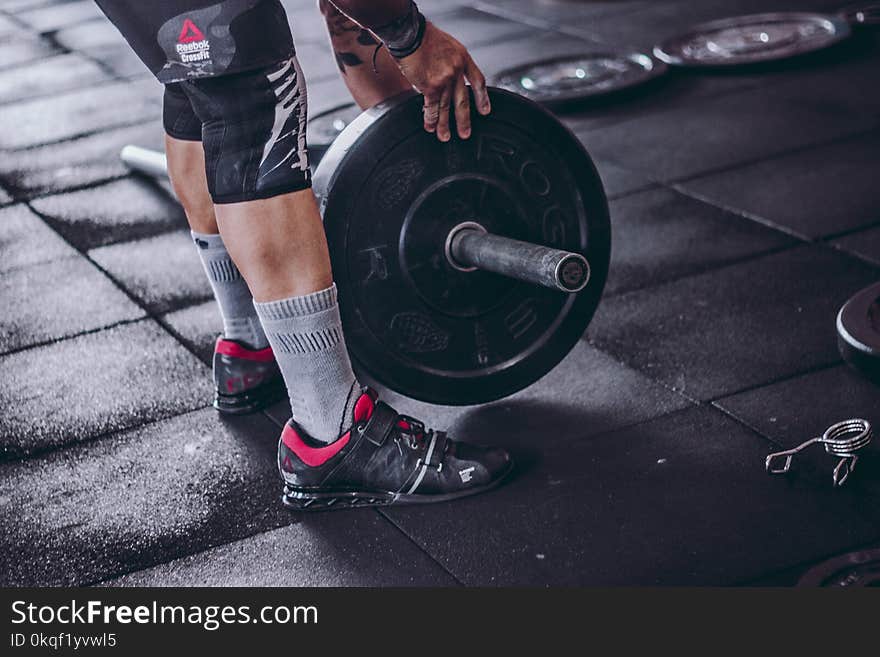 Man Picks Up Black and Grey Barbell