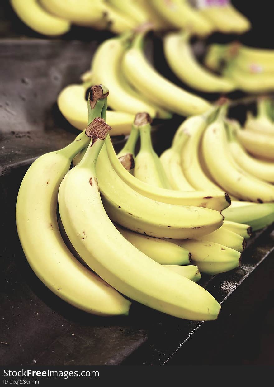 Selective Focus Photo of Bunch of Bananas on Black Surface