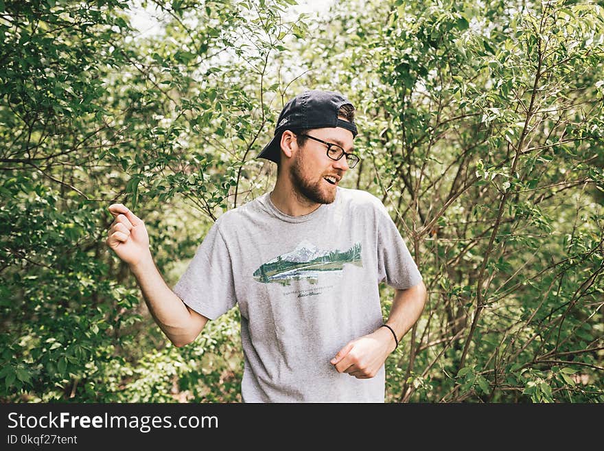 Man Wearing Gray Crew-neck T-shirt Standing Behind Bush