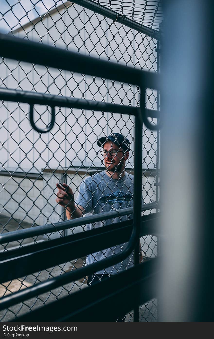 Man in Gray Steel Cyclone Fence