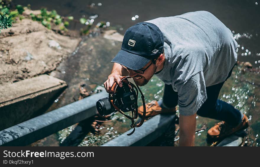 Man Holding Dslr Camera Wearing Cap