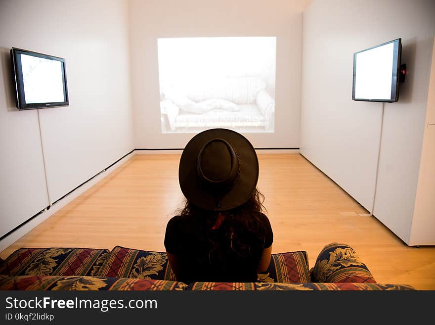 Woman Sitting on Red-and-green Suede Sofa Facing Well Lighted Room