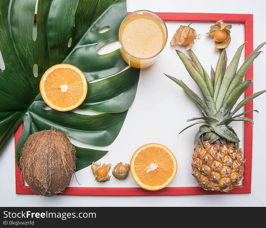 Summer concept, fresh delicious fruit, pineapple, oranges, coconut, orange juice, in a red frame, on white rustic background, sp