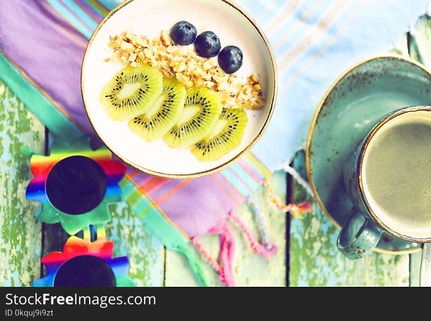 Cup of granola with yogurt and fruit on turquoise background