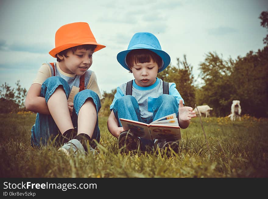 Kids Sitting On Green Grass Field