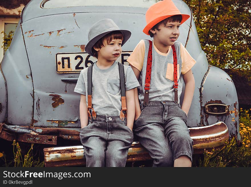 Two Boys Sitting on Vehicle Bumper