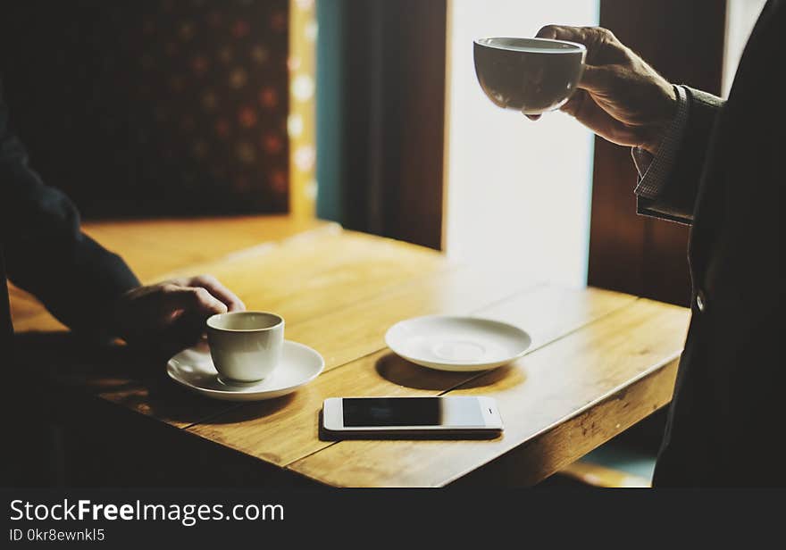 Man Holding Cup Near Table