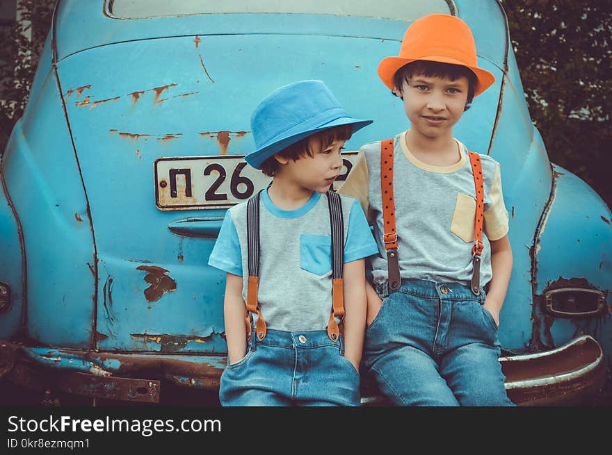 Two Boys Sitting on Blue Volkswagen Beetle Coupe&#x27;s Rear Bumper