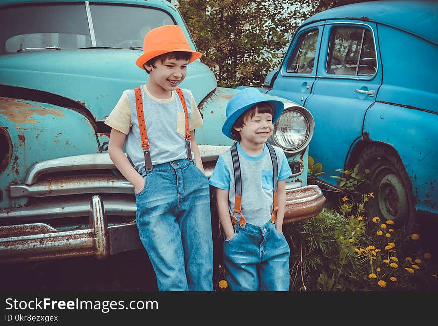 Two Boys Leaning on Classic Teal Vehicle