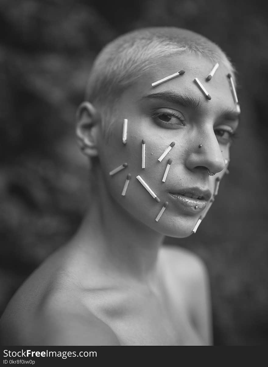 Grayscale Photo of a Person With Matchsticks on Face