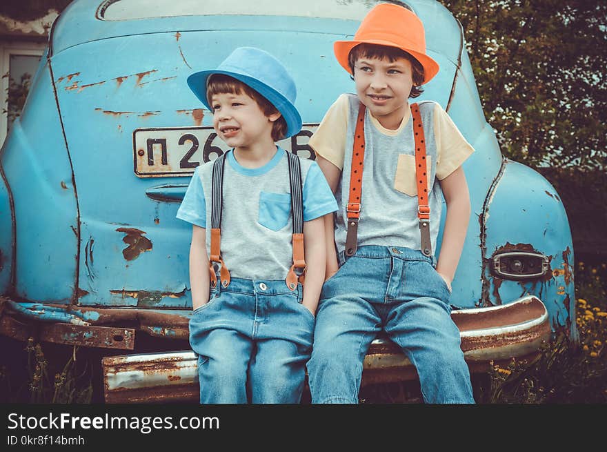 Two Boys Sitting on Classic Blue Car&#x27;s Rear Bumper